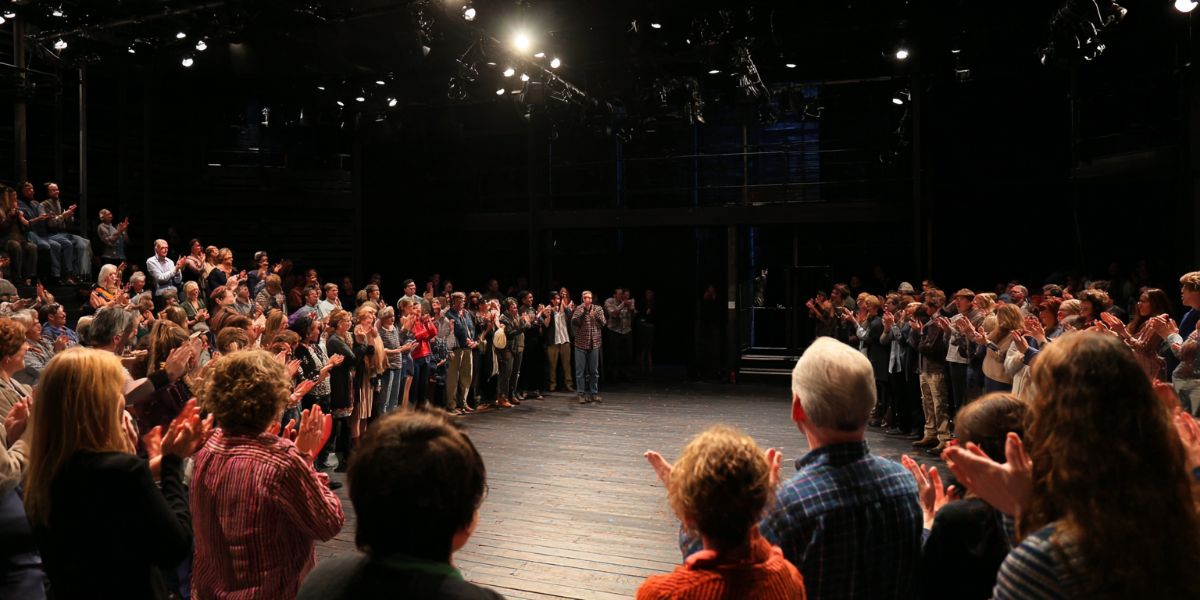 Audience at a small theatre applauding actors
