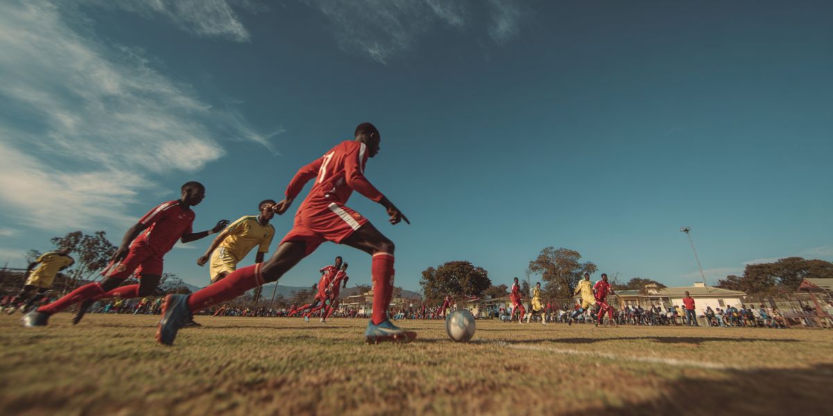 Young guys playing soccer on a dusty pitch in a South African township
